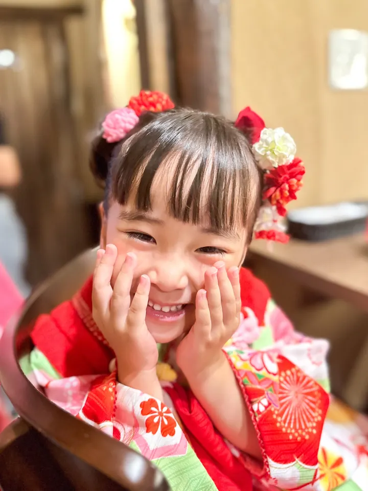 両手をほほに当てて笑う3歳の女の子の七五三着物姿