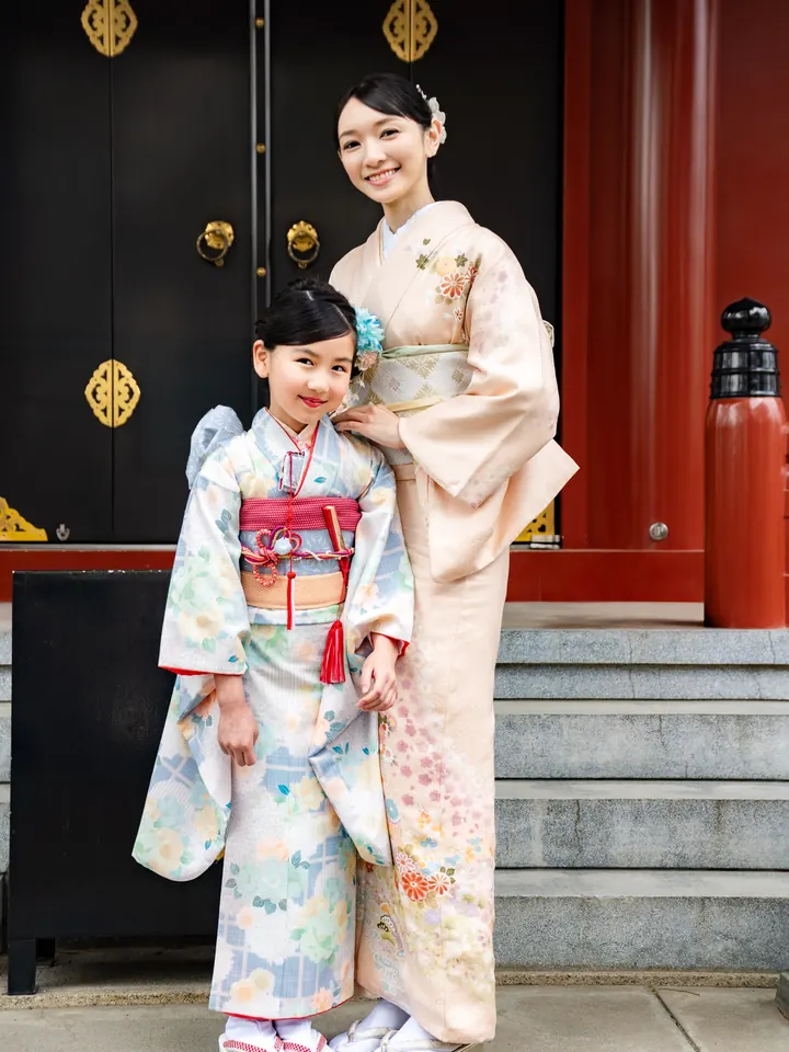 神社の前で母親と並ぶ7歳の女の子の着物姿